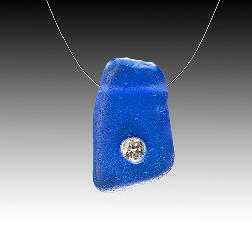 A cobalt piece of genuine beach glass hung delicatley on an invisible chain with a 10 pt diamond set right into it!