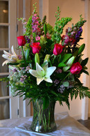 Glass vase with white lilies, pink lilies, pink roses, pink larkspur, bells of ireland
