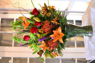 The Paradise- An exotic combination of bright red Proteas, Red roses, Orange Lilies, Purple Liatris, Bells of Ireland, & a nice texture of Curly Willow