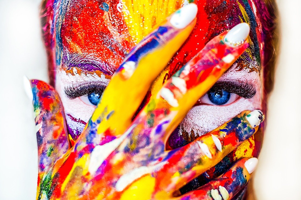 A woman with paint on her face embraces her creative side to heal her chakras.