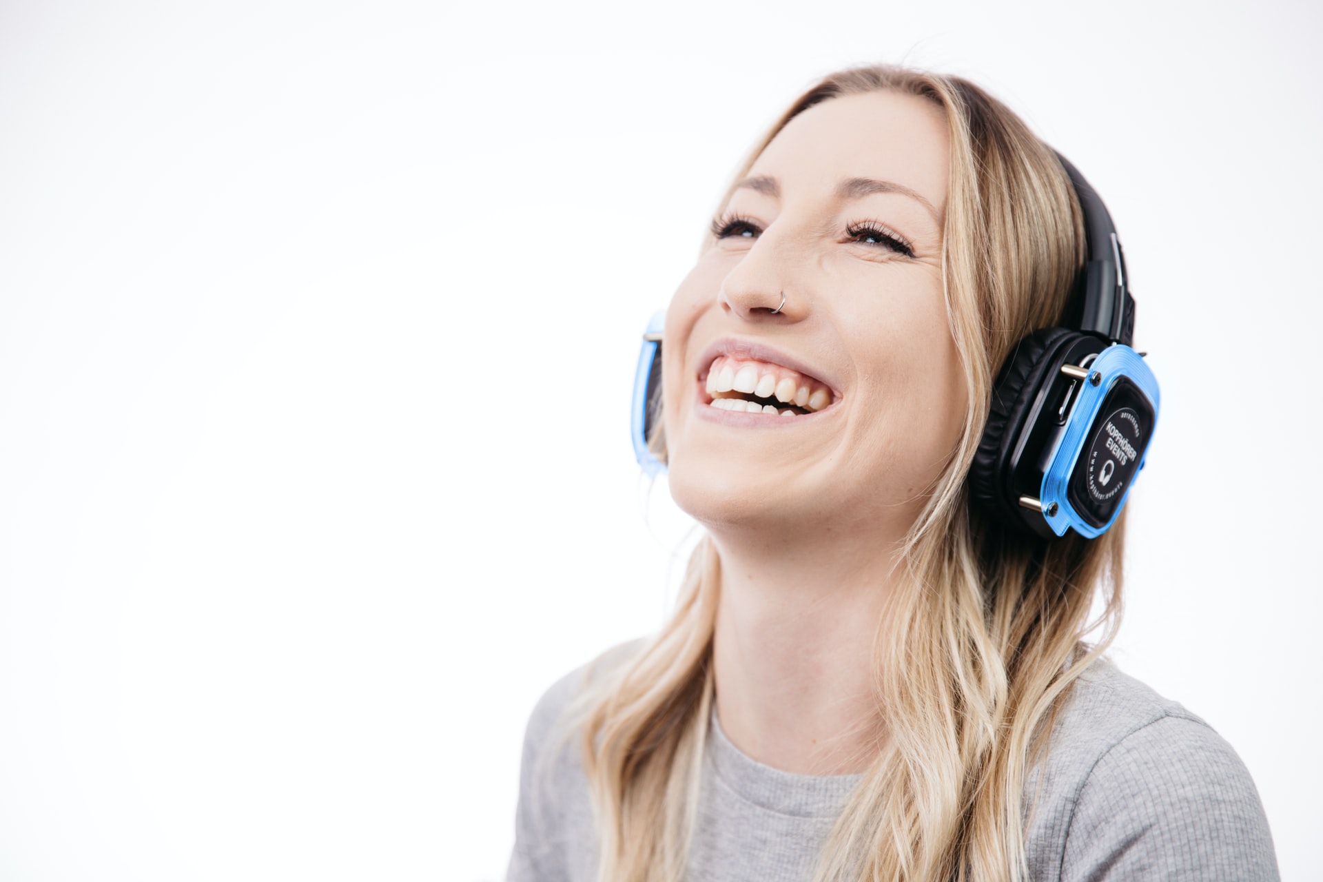 A smiling woman listens to binaurals through headphones.