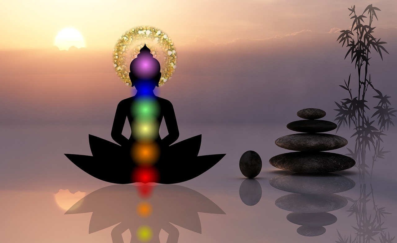 A silhouette of a person meditating with their chakras being shown.