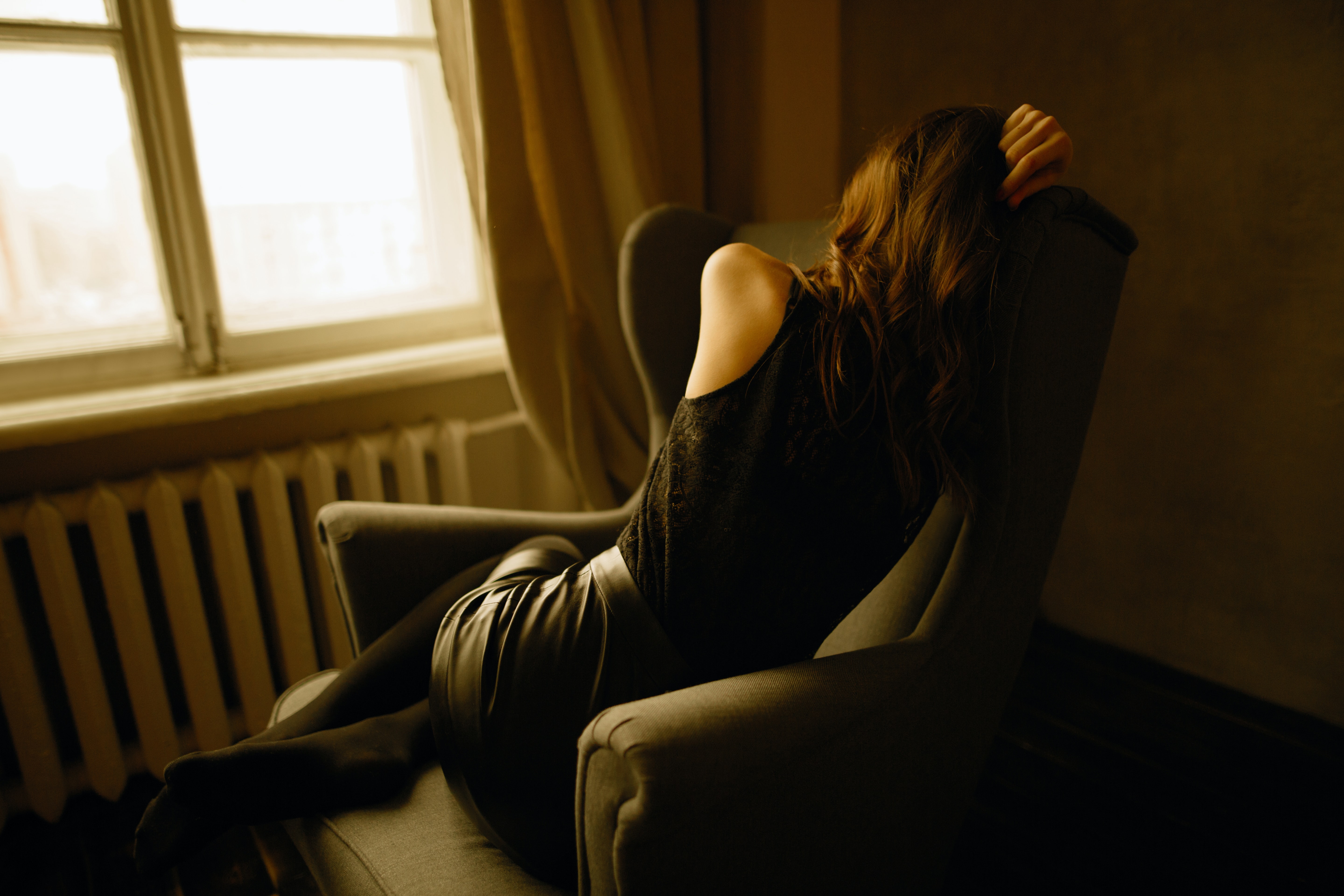 A woman suffering from fatigue lays motionless on a chair while being exhausted.