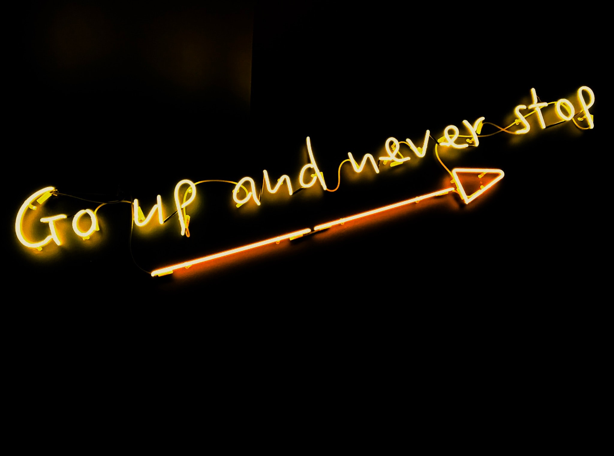A black background with bright words that say go up and never stop.