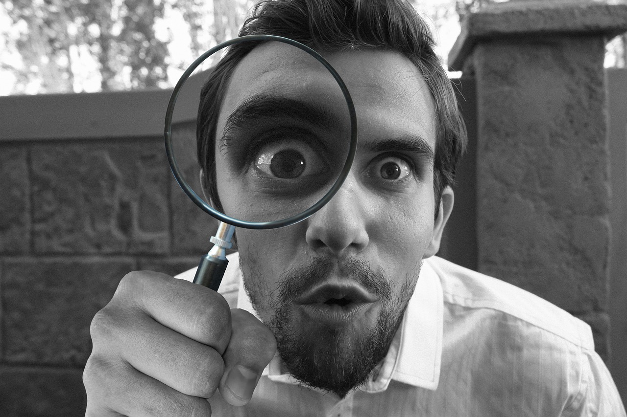 A man hold us a magnifying glass resembling a person doing research.