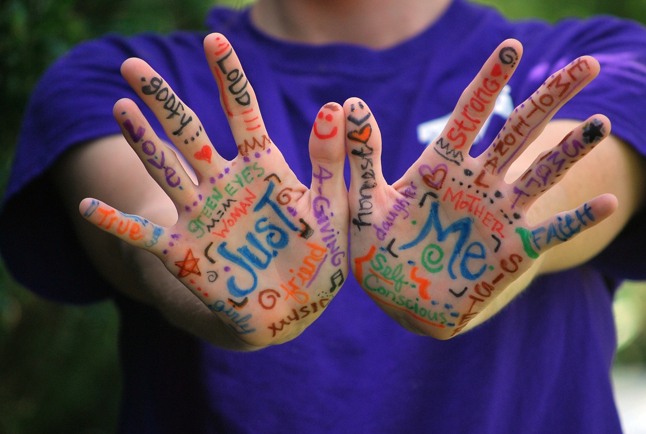 A woman showing her hands that she has creatively painted with different words.