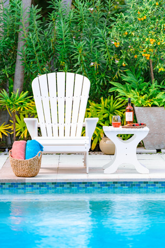 A photograph captures the essence of our Adirondack Chair, showcasing its inviting design on a picturesque pool deck. The chair features rolled front edges and contoured seats for ultimate comfort. The interlocking seat and back, secured by stainless steel fasteners, highlight the chair's robust construction. Customizable design options, including personalized engravings, add a touch of individuality. Bathed in sunlight, this outdoor oasis epitomizes the perfect synergy of quality craftsmanship, durability, and timeless style embodied by our Adirondack Chair.