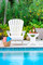 A photograph captures the essence of our Adirondack Chair, showcasing its inviting design on a picturesque pool deck. The chair features rolled front edges and contoured seats for ultimate comfort. The interlocking seat and back, secured by stainless steel fasteners, highlight the chair's robust construction. Customizable design options, including personalized engravings, add a touch of individuality. Bathed in sunlight, this outdoor oasis epitomizes the perfect synergy of quality craftsmanship, durability, and timeless style embodied by our Adirondack Chair.