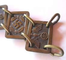 N.S.D.A.P. gorget chain. Bronzed panels of alternating eagle/swastika and swastika/oak leaves held together with brass wire loops. Panels show the markings "RM M1/128". Original era manufacture. Length of 19 original links (one complete side) for the NSDAP Standard Bearers bearers gorget, one of the links has an RZM mark on its reverse. Rare!