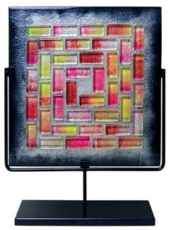 A 17 inch decorative glass square panel featuring grey in the background with red, yellow and clear glass tiles fused in a pattern