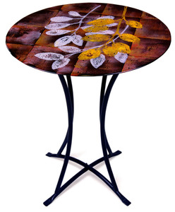 Geometric patterns in black yellow and red are the backdrop for the leaves on this fused glass cafe table