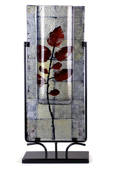 A tall vase, at 24x10in, featuring silevers and geometric squares.  Adorned with red leaves