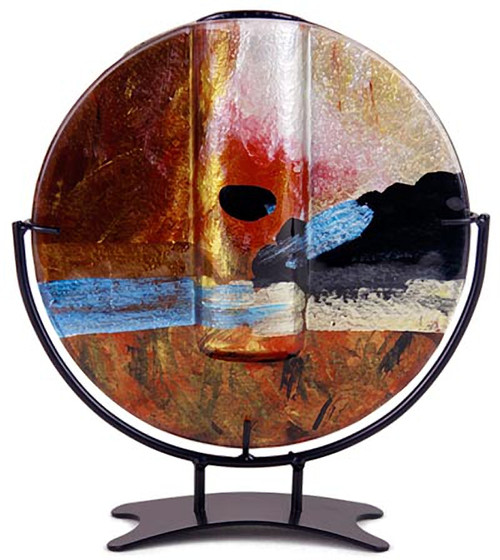 This round shape bud vase incorporates fused glass with red, blue, yellow gold and black.  In the Horizon series. Stand included