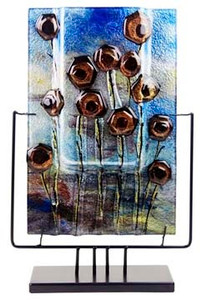 A rectangular fused glass vase with muted earthy colors, stylized flowers and pretty blue horizon.  Stand included