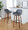 Daniella 30" Contemporary Fixed-Height Barstool with Swivel in Walnut Wood and Grey Faux Leather with Round Black Metal Footrest- Set of 2 — lifestyle photo 2