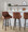 Hannah 30" Transitional Fixed-Height Barstool with Swivel in Walnut Glazed Wood and Camel Faux Leather with Round Black Metal Footrest- Set of 2 — lifestyle photo 1