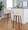 Toriano 30" Mid-Century Modern Fixed-Height Barstool with Swivel in Walnut Wood and Cream Faux Leather with Round Chrome Metal Footrest- Set of 2 — lifestyle photo 1