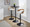 Grotto Contemporary Adjustable Barstool in Black Metal, Whitewashed Wood, and Oat Fabric with Rounded T Footrest — lifestyle photo 2