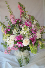 Clear glass vase overflowing with a pretty mix of fresh flowers in soft hues.