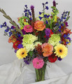 Bright mix of fresh flowers arranged in a trumpet vase.