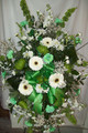 Standing funeral spray of green and white fresh flowers and green ribbon.