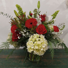 Lush vase of fresh greens, and premium red and white flowers.