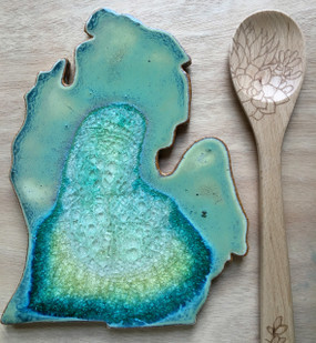 Bring your love of Michigan to your dinner table with this stunning handmade trivet.  Resembling the crystalline, geological complexity of geode cross-sections, this stoneware and glass glazed trivet bring handcrafted beauty to functional home decor. The organic interaction of stoneware, glass, and colored glazes produces a unique, crackled surface with fascinating variations that make each trivet one-of-a-kind. Handmade by Kerry Brooks in Minneapolis, Minnesota.
Due to the handmade nature of this item, each is unique and will vary.  Size 8x11
