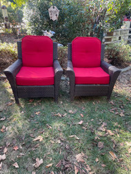 Pair of dark faux wicker patio chairs with red cushions
