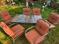 5 foot bronze finish glass top patio table with 6 chairs and cushions