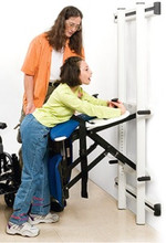 User is wheeled to Support Station, grabs the handholds, and lifts (is lifted) to standing position. When kneeboard is in place (shown in picture), a rolling commode can be moved in. When kneeboard is not used, the Support Station can be pivoted to a standing toilet. Or the client can be diapered with greater ease and better hygiene.