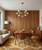 A warm and inviting Mid-Century Modern dining and living space that beautifully demonstrates how extensive Spirit Birch wood paneling can integrate open-concept functional zones. The room relies on a palette of rich wood tones, earthy mustard accents, and clean, iconic retro lines to create a cohesive, curated environment.