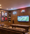 A classic, upscale home bar and sports lounge that perfectly captures a comfortable, traditional clubroom feel. Designed as an inviting entertainment hub, the space leverages full-wall Spirit Birch wood paneling to create a warm, cozy, and sophisticated atmosphere for relaxing or watching a game.