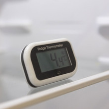 Close-up of digital fridge thermometer showing temperature range from −9.9 °C to +49.9 °C.
