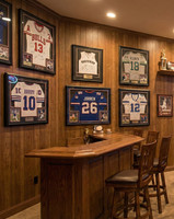 A classic, upscale home bar and sports lounge that perfectly captures a comfortable, traditional clubroom feel. Designed as an inviting entertainment hub, the space leverages full-wall Spirit Birch wood paneling to create a warm, cozy, and sophisticated atmosphere for relaxing or watching a game.