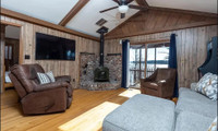 The room features vintage, cabin-style vertical Swampland Cypress wood paneling, characteristic of mid-to-late 20th-century residential interiors.
