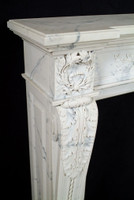 Wreath corner blocking at each corner of the Auguste marble mantel.