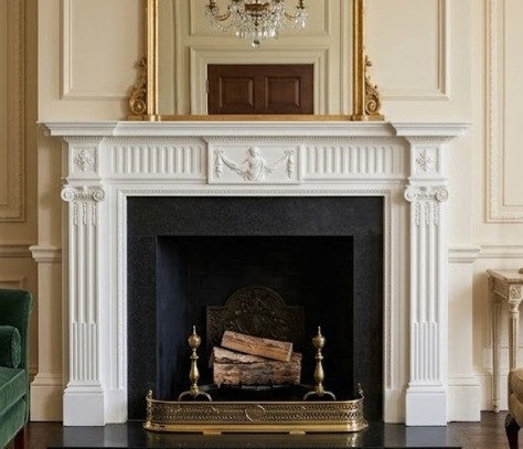 This formal parlor provides an exceptional, historically cohesive setting for the Neoclassical-style white mantel from image_8bd460.png. Embracing the clean symmetry, refined fluting, and delicate plasterwork characteristic of the late 18th and early 19th centuries, the room is thoughtfully styled to emphasize architectural elegance and sophisticated comfort.