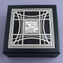 Skunk memory box in silver with black glass and iridescent pearl under the center design