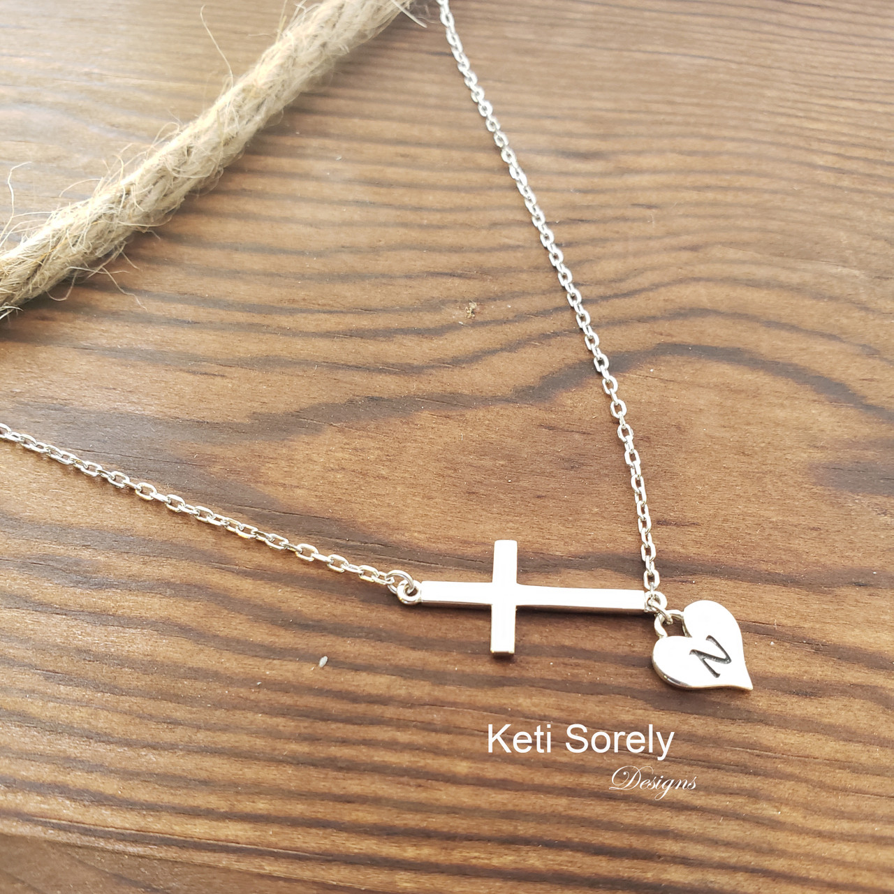 Sideways cross necklace with engraved initial on the heart pendant