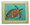 A framed tile with a painting of a green turtle in Barbados by Sue Trew