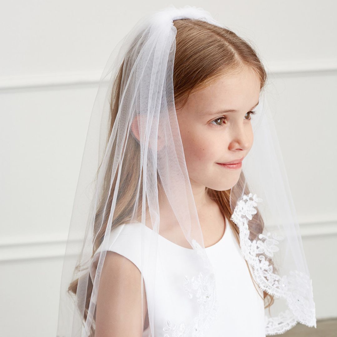 a little girl wearing a white veil and dress