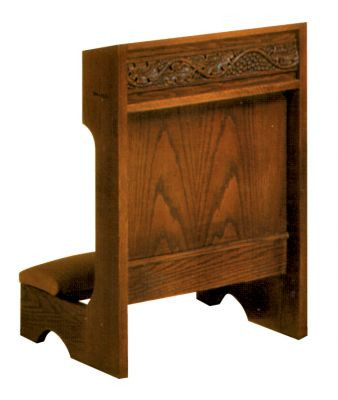 Rectangular wooden structure with a kneeling pad and decorative design carved into the front.
