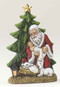 Santa with a lamb kneeling next to a Christmas tree and holding a sleeping baby Jesus. 