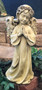 The front view of a cement praying angel with arms brought together in prayer displayed in an outdoor garden.