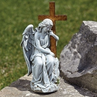 Feminine angel sitting on a stone with arm wrapped around a large cross