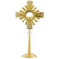 Gold plated monstrance with a golden sun in front of a golden cross 
