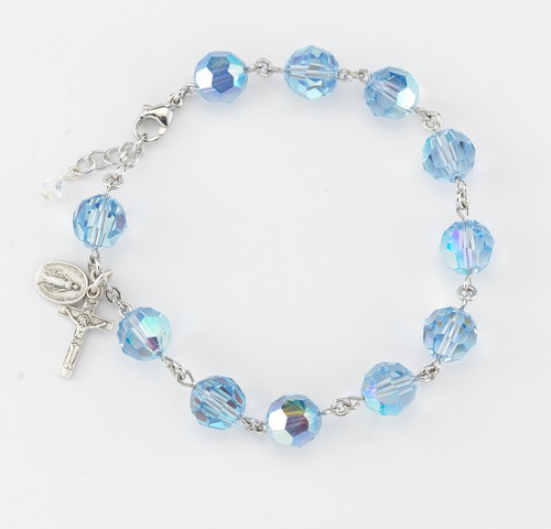 10mm Round Faceted Swarovski  Light Sapphire Rosary Bracelet. Sterling silver miraculous medal and crucifix with sterling silver links or rhodium plated brass links. Comes in a deluxe velour gift box. Made in the USA.