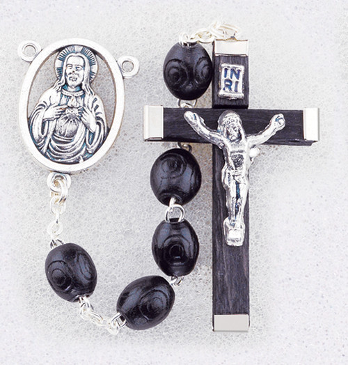 Black Boxwood Beads Rosary. 7 x 8mm black oval carved boxwood beads rosary has a silver oxidised Sacred Heart of Jesus Centerpiece and the cross is wood with silver oxidised corpus. Rosary measures 19".