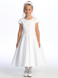  Little girl smiling in a white Communion dress with embroidered tulle.