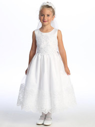 Little girl smiling in a white Communion dress with embroidered tulle.